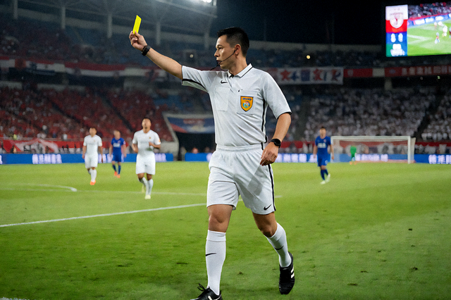 足球比赛中裁判向球员出示黄牌的比赛瞬间